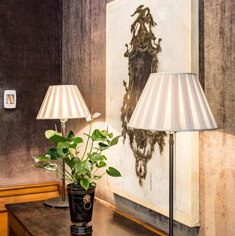 white empire lamp shades on table by painting